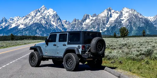 A Jeep with reverse mount wheels sits among mountain scenery
