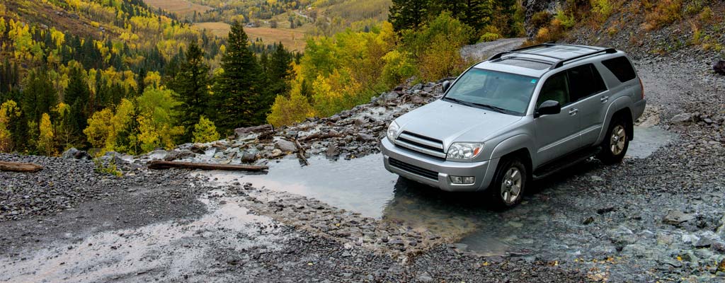 SUV driving on wet gravel road.