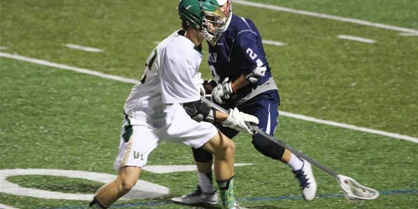Two lacrosse players face off on the field.