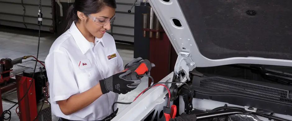 Female employee performing a battery test on a white pickup.