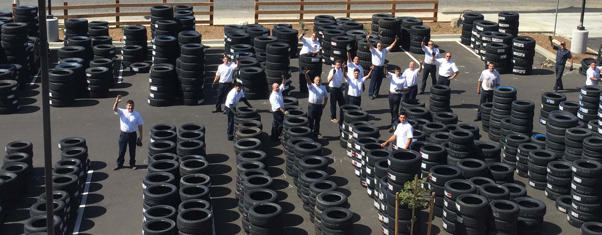 Amidst stacks of new tires, Les Schwab employees wave hi from the parking lot of the Norco location.