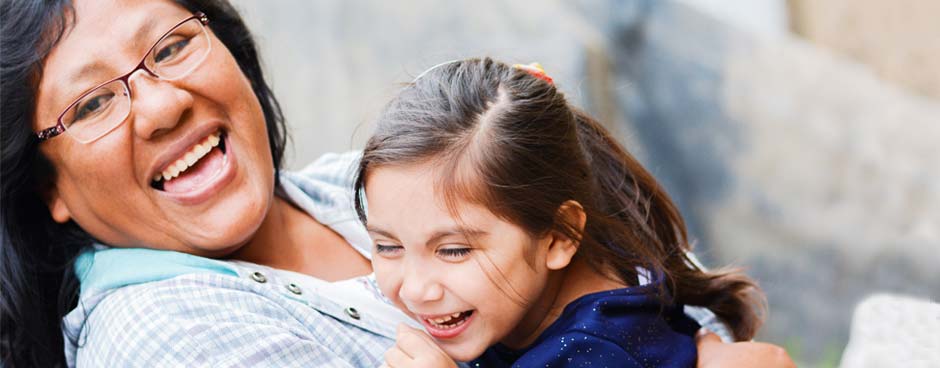 A hispanic mother and daughter laughing.