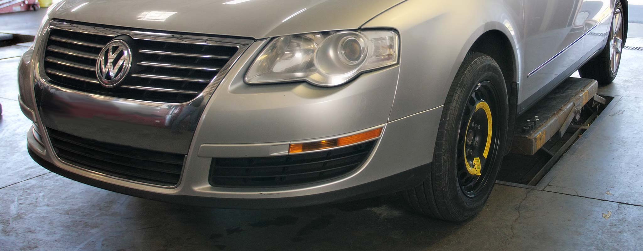 Car with spare tire installed ready to be lifted in repair bay.