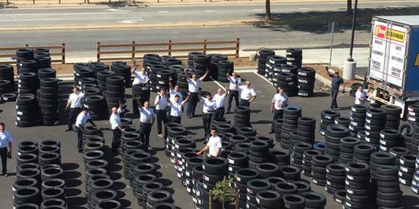 Amidst stacks of new tires, Les Schwab employees wave hi from the parking lot of the Norco location.