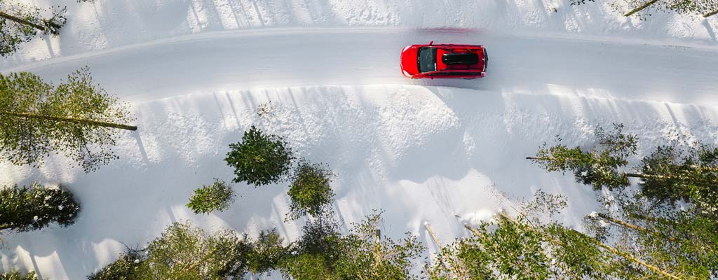 Red car driving on snowy road