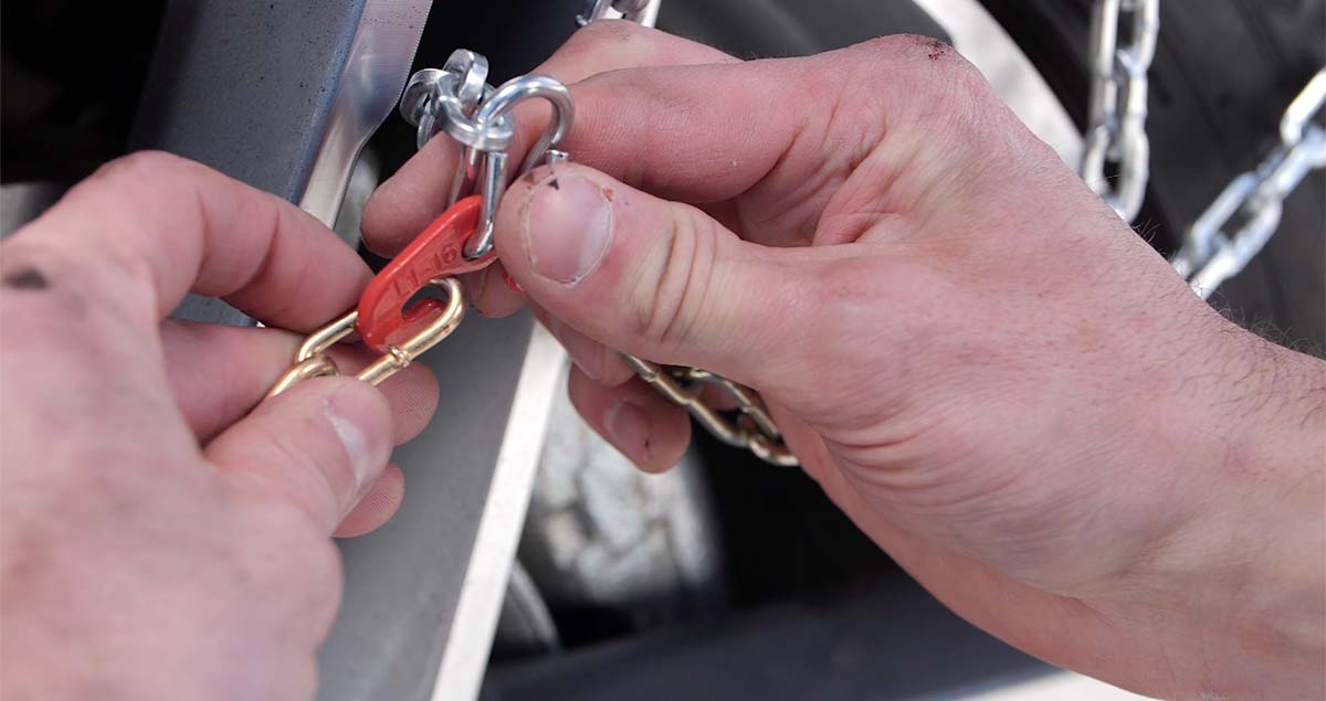 Man connecting the hook on the top of his tire chains.