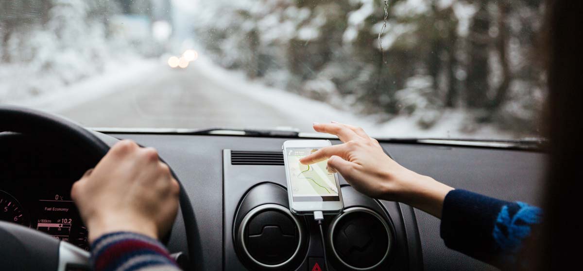 Two people using mobile phone for navigation while driving over a mountain pass