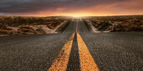 A sunset at the end of a long straight road.