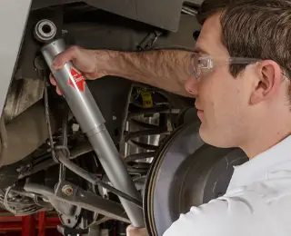 Les Schwab employee installing a new shock to a vehicle
