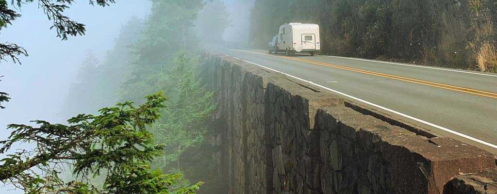 Camper being pulled on a misty highway