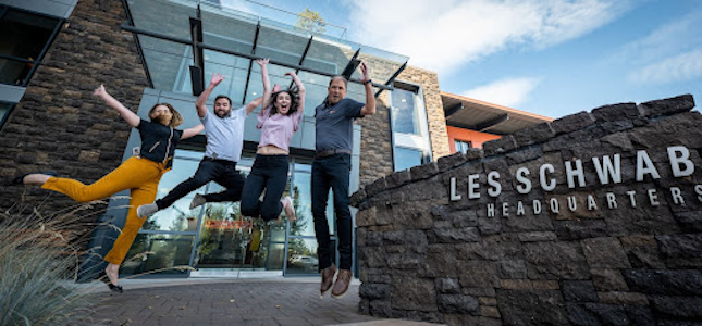 Four Les Schwab employees jumping in front of the Headquarters building in Bend, Oregon