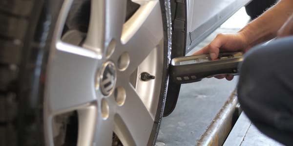 Tire technician resetting a TPMS monitor using a tool.