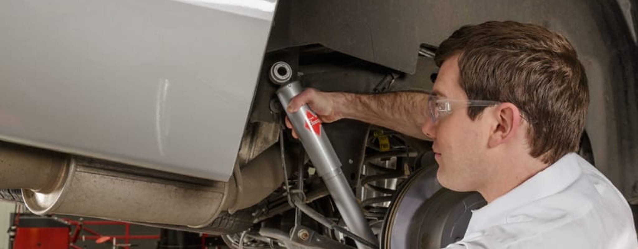 A Les Schwab technician inspecting a car's shocks