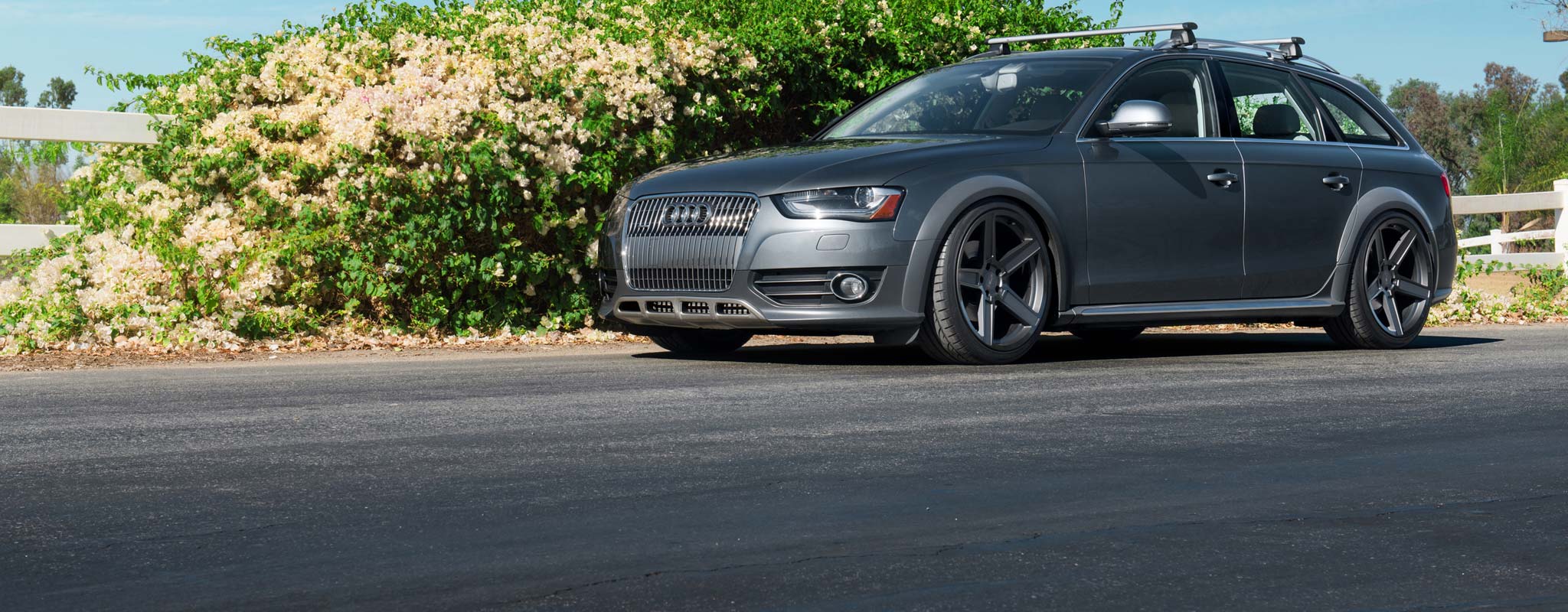 Grey Audi wagon with custom wheel and a roof rack.