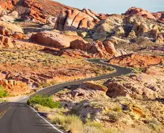 A two-lane road zig-zags through orange desert scenery.