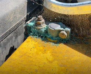 Cleaning corrosion from a battery terminal with a wire brush.