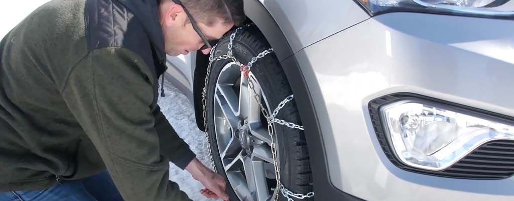 A man putting snow chains on their CUV.