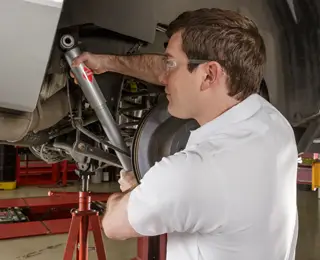 A Les Schwab technician inspecting a car's shocks