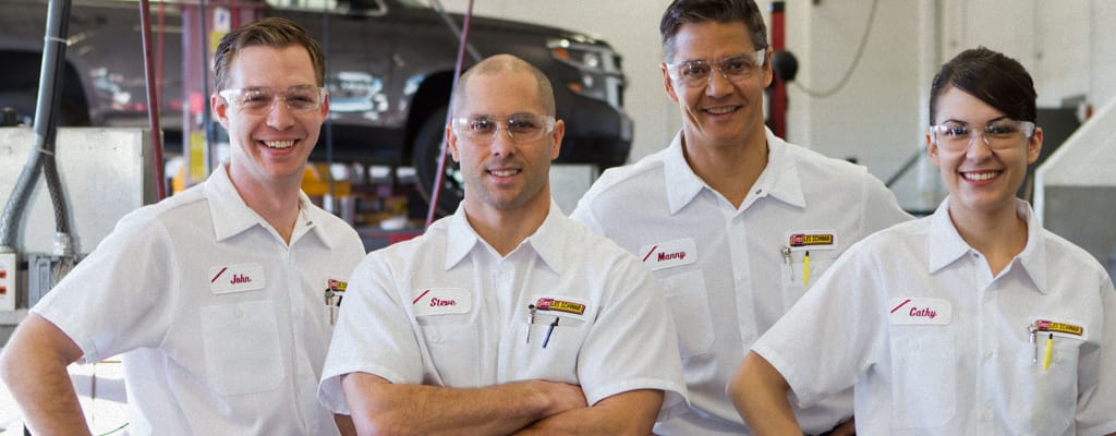 Four Les Schwab technicans pose inside a garage.