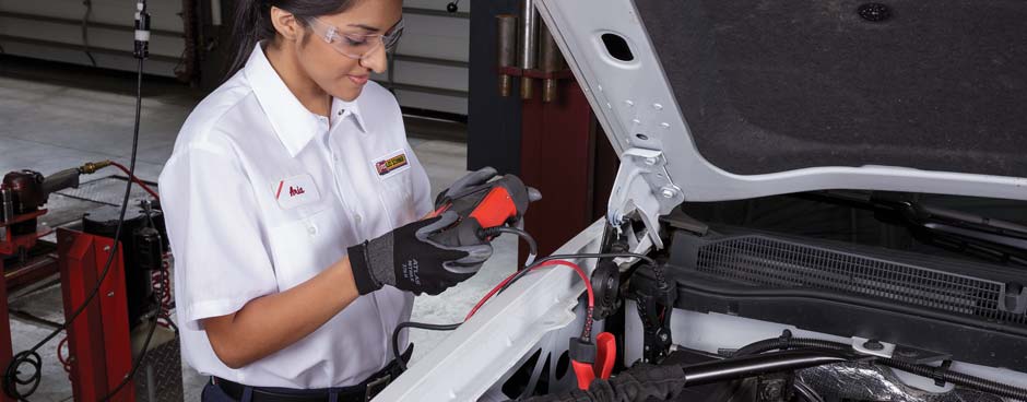 Female employee performing a battery test on a white pickup.