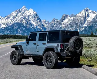 A Jeep with reverse mount wheels sits among mountain scenery
