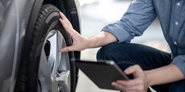 Person checking his tire with a tablet in his hand