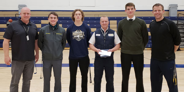 A Les Schwab manager poses in a gym with an Oregon sports team.