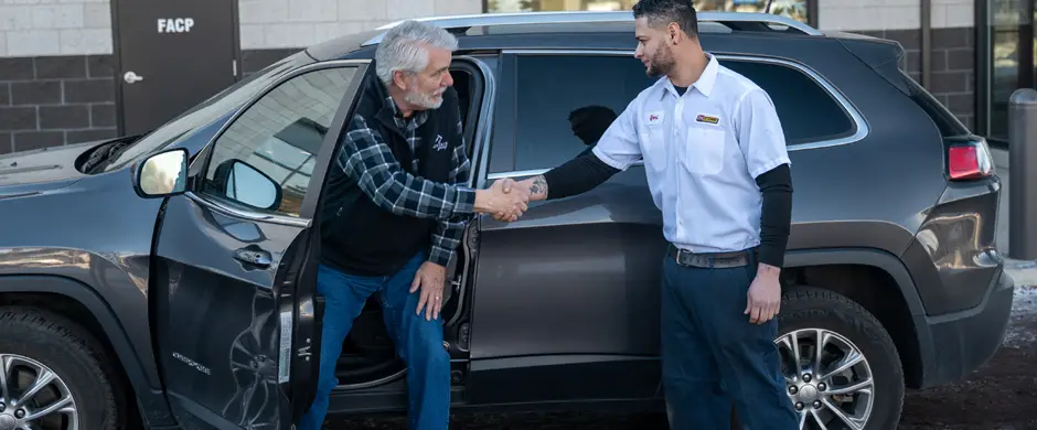 A Les Schwab employee meeting a customer at their vehicle