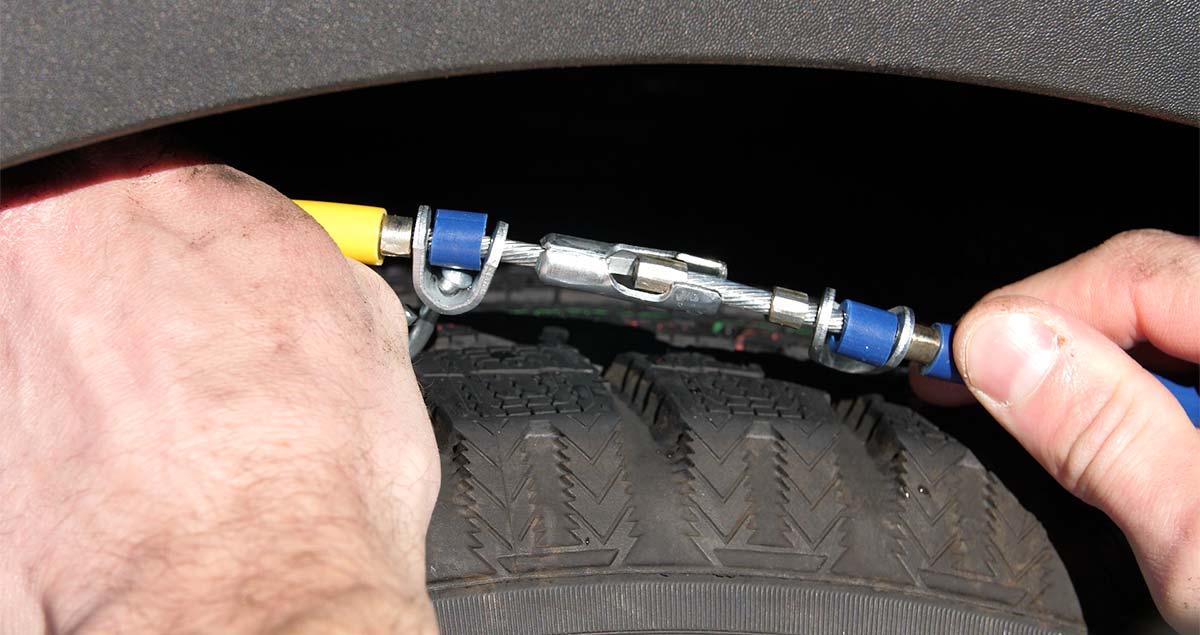 Man connecting ends of tire chain around tire.