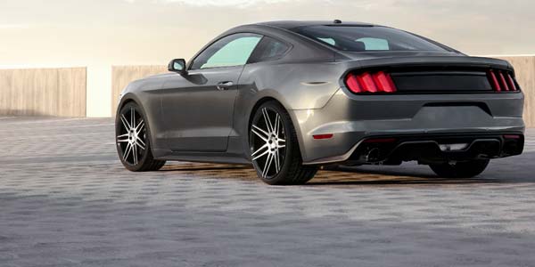 Grey Mustang parked on a cobblestone parking lot.