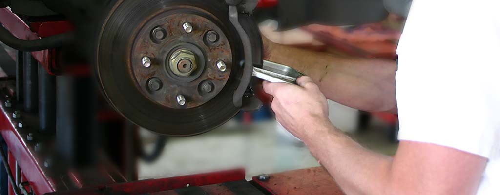 A Les Schwab technician working on a brake caliper.