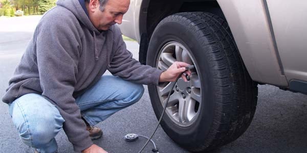 Man filling his car tire with air.