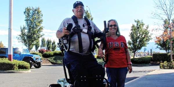 George Myers in a wheelchair that allows him to stand, next to wife Debbie.