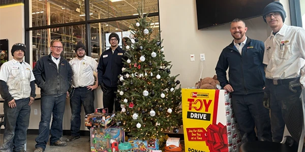 Les Schwab employees surround Christmas tree and donated toys