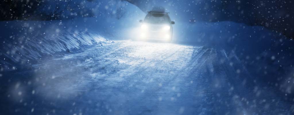 Car driving on a snow packed road at night
