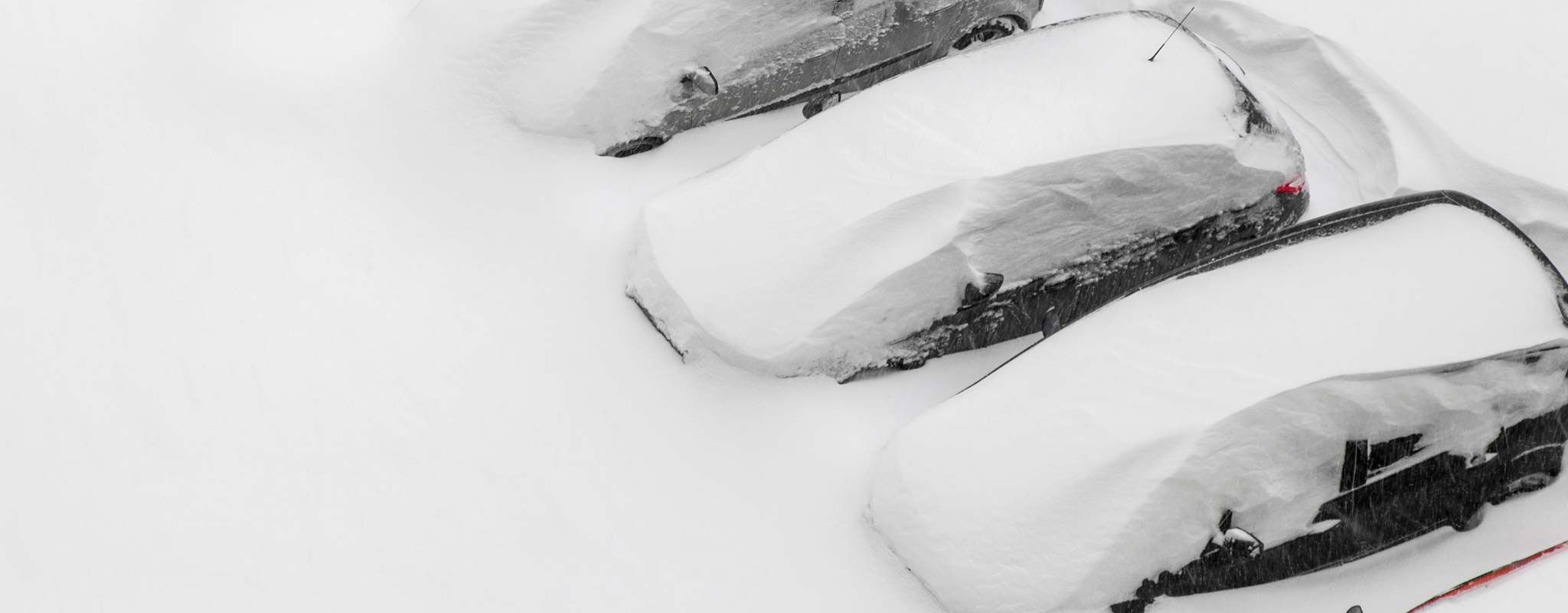 Cars buried under a large snowfall.
