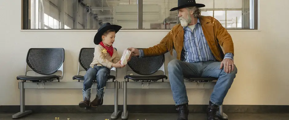 Cowboy sharing popcorn with a small boy