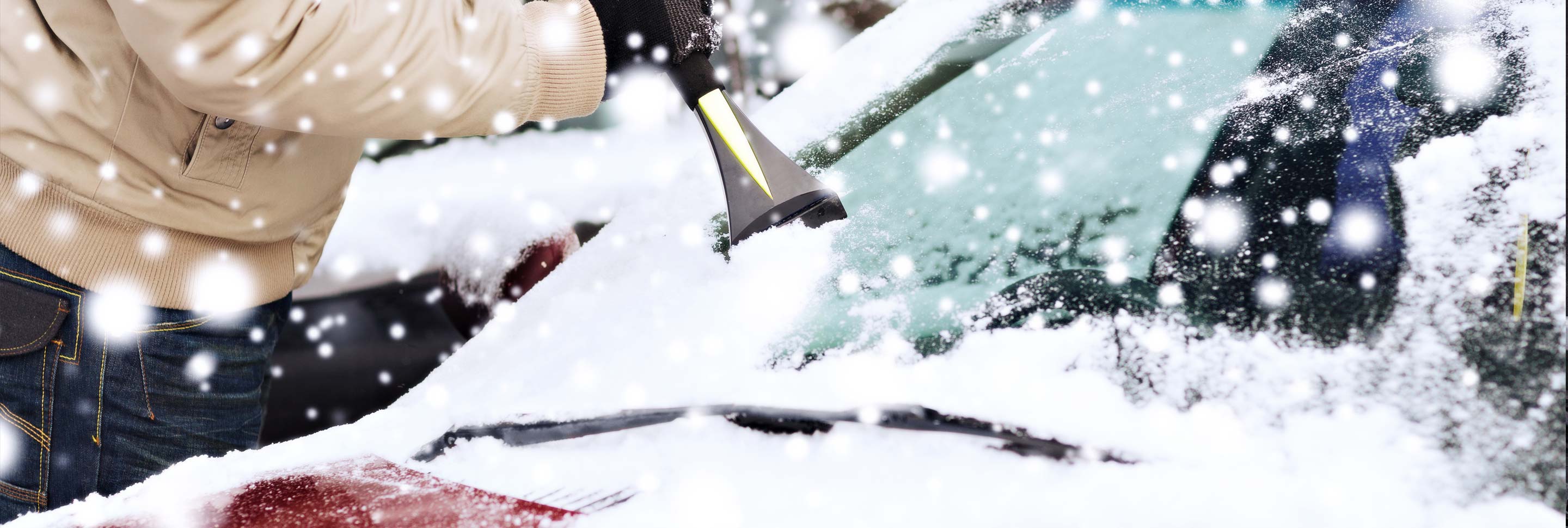 A man scraping ice from his car window.