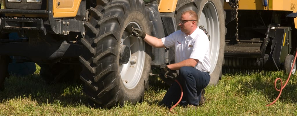 A Les Schwab technician checks the air pressure of a tractor tire.