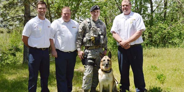 Three Les Schwab managers pose with a military dog and its owner, Frank Wehner.