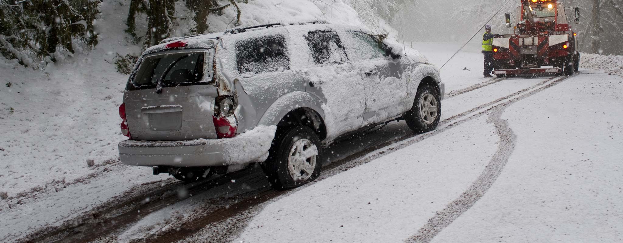 SUV getting towed out of a snowy ditch.