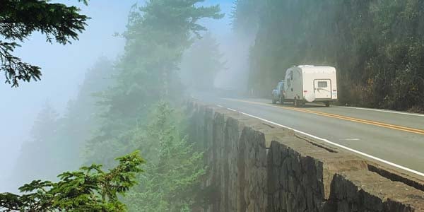 Camper being pulled on a misty highway