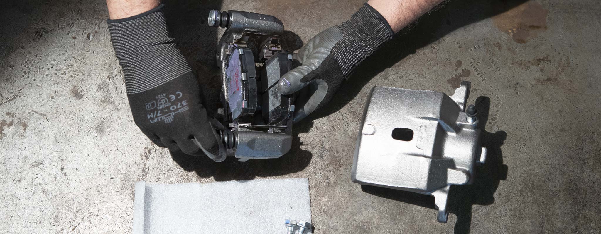 A Les Schwab technician adding new brake pads to a remanufactured brake caliper.