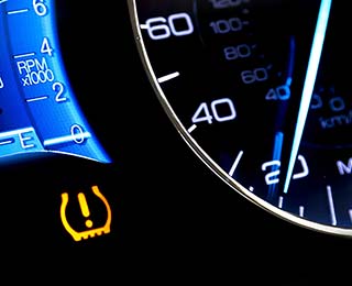 A lighted car dash with the TPMS light illuminated.