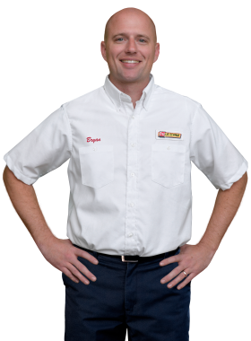 A Les Schwab technician stands arms akimbo. His name is Bryan