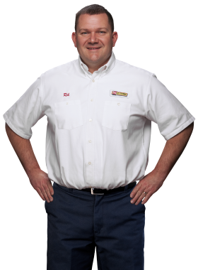 A Les Schwab technician stands arms akimbo. His name is Rik