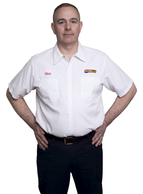 A Les Schwab technician stands arms akimbo. His name is Michael